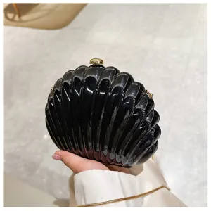 Detail of a glossy black shell-shaped evening clutch with elegant gold hardware