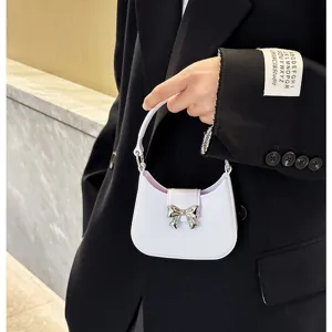 Stylish white PVC jelly bag with metallic bow detail held by model in black blazer