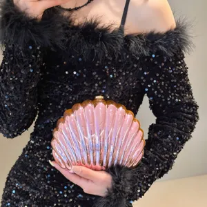 Iridescent pink shell-shaped evening clutch bag held against a black sequin dress.