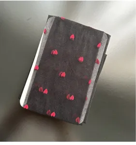 Close-up view of sheer black tights featuring cute red heart velvet patterns and white card.
