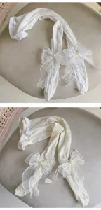 Vue détaillée de collants blancs pour enfants avec nœuds en organza et perles.