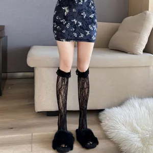 Detailed view of women's black lace knee high socks paired with furry slippers and skirt.