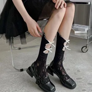 Nahaufnahme von schwarzen Damen-Spitzenwadenstrümpfen mit weißen Schleifenausschnitten, Lolita.