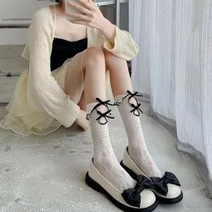 Detailansicht von Damen Spitzenwadenstrümpfen mit schwarzen Schleifen und Lolita Schuhen.