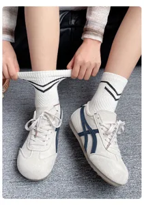Primer plano de calcetines blancos de media pantorrilla para mujer con rayas negras y elástico.