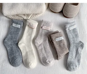 Close-up of cozy women's winter thick wool knit slouch socks with cute fabric label details.