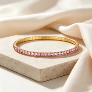 Close-up of a gold stainless steel tennis bracelet with pink crystals on stone.