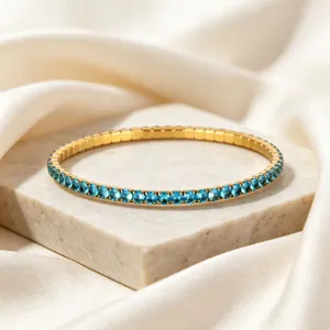 Close-up detail of a gold stainless steel elastic bracelet with blue zircon stones