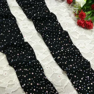Detailed view of black mesh fishnet stockings sparkling with rhinestones on delicate lace.
