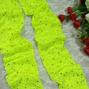 Close-up detail of neon yellow rhinestone mesh stockings, sparkling crystal stones, sexy fashion.