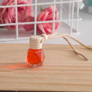 Detailaufnahme eines hängenden Auto-Parfümfläschchens mit Rauten-Glasdesign und Holzverschluss.