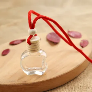 Transparent apple shape car perfume empty bottle with red rope and wooden cap detail closeup.