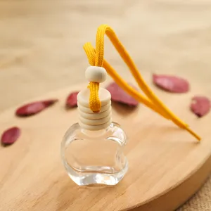 Transparent apple-shaped glass car perfume bottle with wooden cap and yellow hanging cord.