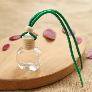 Detailed view of a transparent apple-shaped empty car perfume glass bottle with green rope.