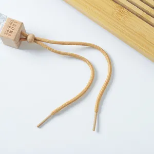 Gros plan détail du bouchon en bois de flacon diffuseur de parfum avec cordon et perle.