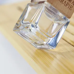 Détail d'un flacon de parfum de voiture en verre transparent au design facetté et bois.