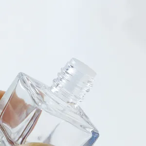 Gros plan détaillé du col et du filetage de flacon de parfum en verre transparent.