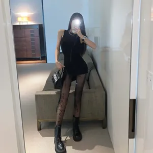 Detail shot of sexy black sleeveless dress paired with printed tights and edgy boots for night out.