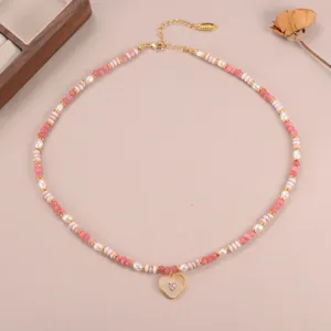 Elegant detailbeeld van een roze kralenketting met een goudkleurige hartjeshanger.