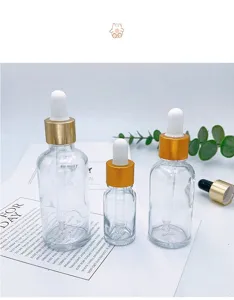 Detailed view of clear glass dropper bottles with gold caps and white bulbs for cosmetics.