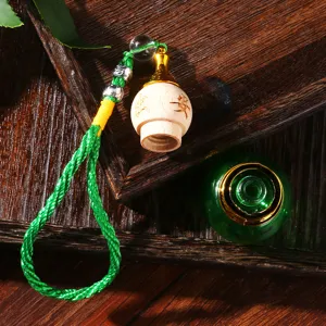 Detailansicht eines Autoparfümanhängers mit gravierter Holzkappe und grüner Glasflasche