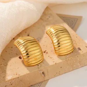 Close-up of golden stainless steel shrimp-style stud earrings with ribbed texture