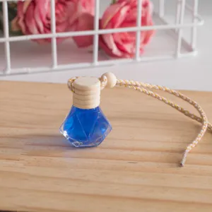 Detailaufnahme der rautenförmigen Autoparfumflasche mit blauer Flüssigkeit und Holzkappe.