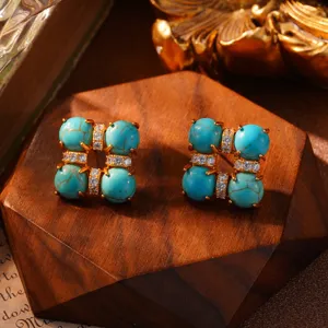 Detailopname van etnische turquoise oorknopjes met gouden afwerking