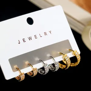 Detailopname van drie paar elegante gouden en zilveren creolen met zirkonia-pavé