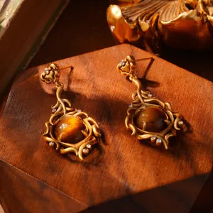 Detailopname van het ingewikkelde gouden patroon en de tijgeroogsteen van deze oorbellen