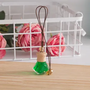Car hanging perfume bottle pendant with green liquid and wooden cap for auto interior decor.
