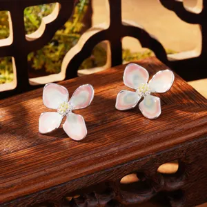 Detail view of Monet-inspired enamel water lily flower stud earrings on a wooden stand