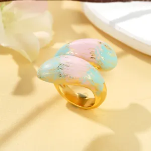 Gros plan d'une bague dorée avec finition peinture à l'huile rose et bleue