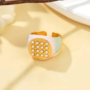 Vue détaillée d'une bague dorée avec émail pastel et incrustation de perles fines