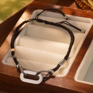 Primer plano de pulsera de acero de titanio con cordón trenzado negro en estuche