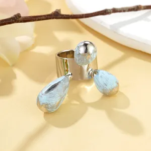 Détail artistique d'une bague argentée avec des gouttes bleu clair à texture unique