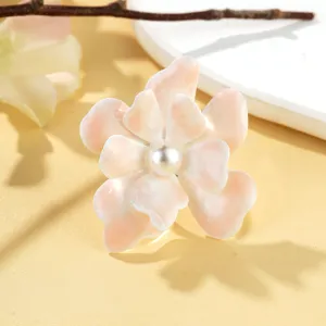 Détail en gros plan d'une bague fleurie rose clair texturée avec une perle centrale