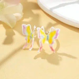 Gros plan d'une bague ouverte argentée ornée de deux motifs papillon en émail coloré.