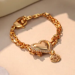 Detailed macro view of a gold-plated double-chain heart bracelet with crystal accents.