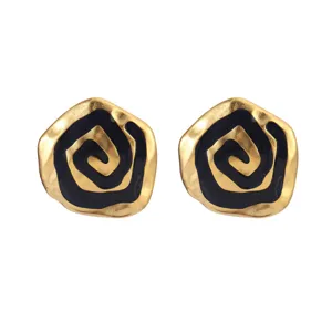 Detailed macro view of vintage gold and black enamel rose spiral pattern stud earrings