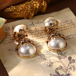 Close-up of vintage French palace style gold pearl earrings on aged paper