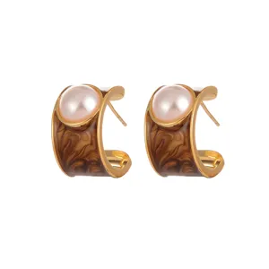 Close-up of vintage Maillard C-shaped earrings with faux pearl and brown enamel