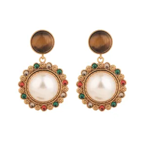 Détails macro de boucles d'oreilles vintage dorées avec œil de tigre et perles