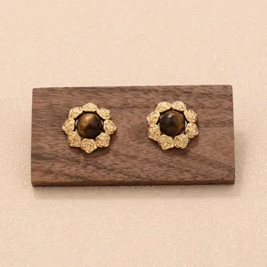 Vue macro détaillée de boucles d'oreilles vintage en or rose avec pierres œil de tigre