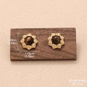 Détail de boucles d'oreilles vintage style Maillard avec œil de tigre brun et bord doré