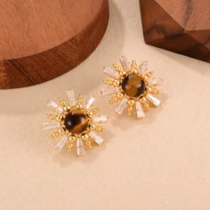 Vue détaillée de boucles d'oreilles soleil vintage avec pierre œil de tigre et cristal.