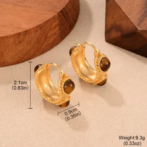 Macro detail of vintage gold C-shaped hoop earrings inlaid with brown tiger eye stones