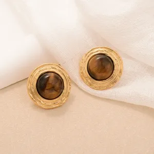 Macro view of vintage round earrings featuring tiger eye stones and golden texture