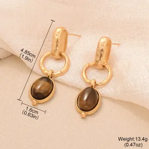Gros plan détaillé de boucles d'oreilles dorées vintage avec œil de tigre ovale