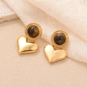 Gros plan détaillé de boucles d'oreilles cœur vintage dorées avec œil de tigre.